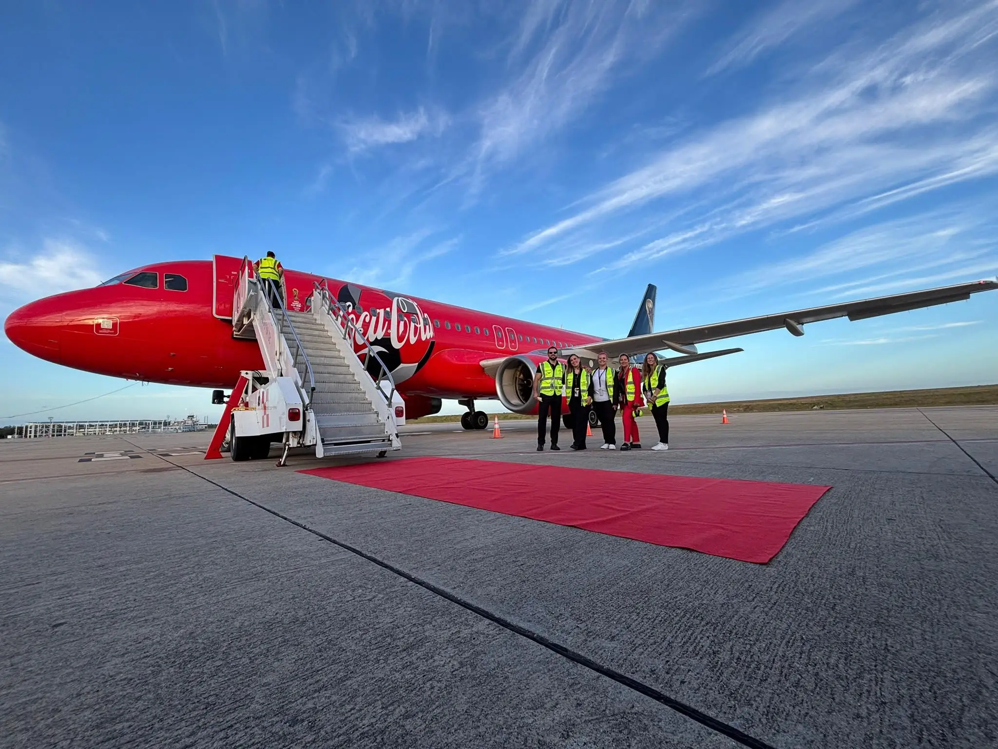 Ground handling team next to an airliner with its airstair down and a red carpet on the Carrasco apron