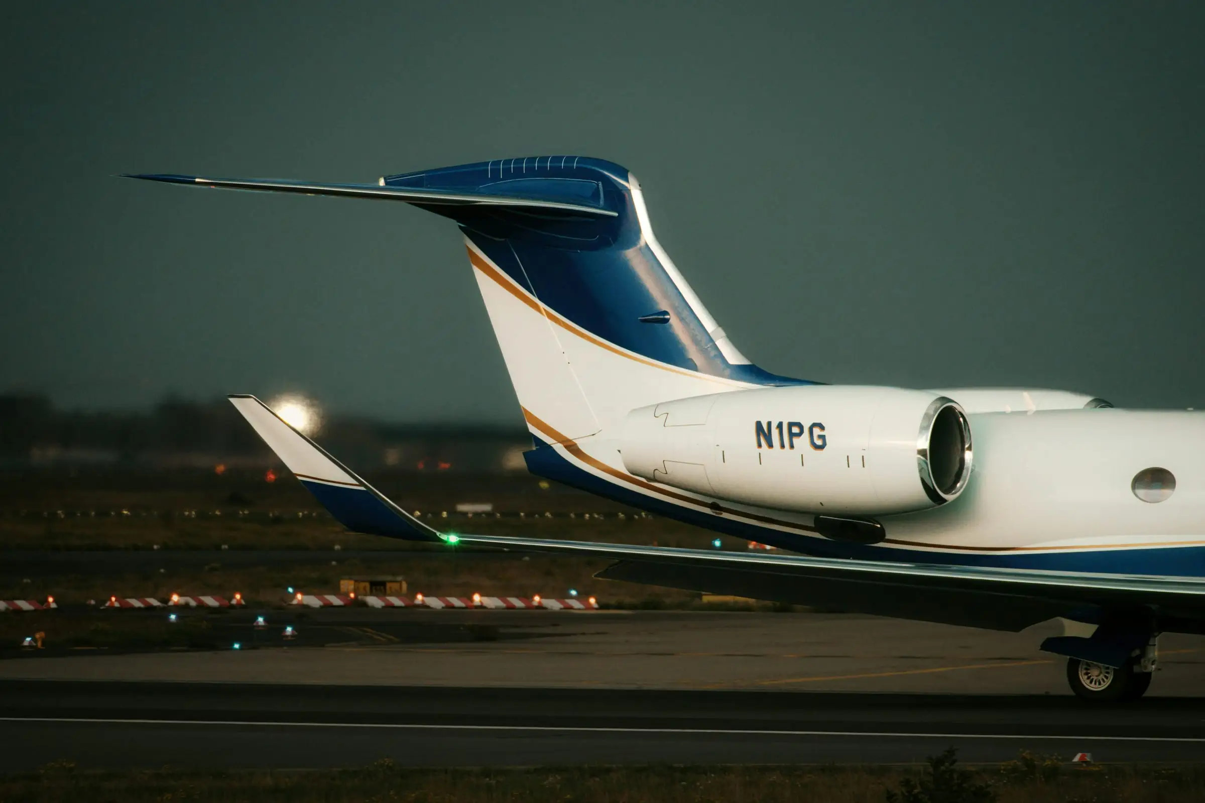 Tail and engine of a private jet on an airfield at dusk