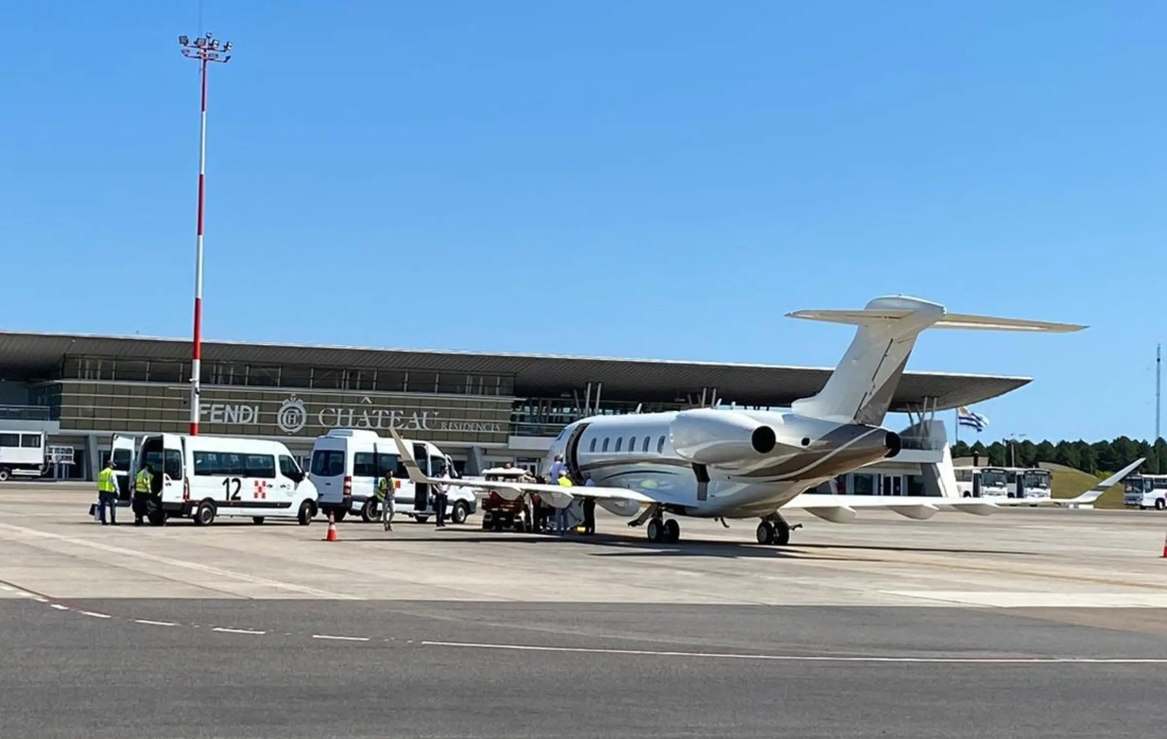 Business jet with handling vans and ground crew in front of the Punta del Este airport terminal