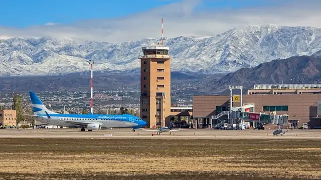 Torre de control y terminal del Aeropuerto Internacional de Mendoza, con un avión de línea rodando y los Andes nevados al fondo